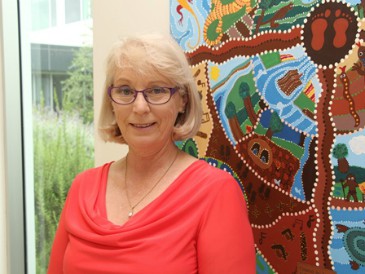 Woman standing in corridor in front of Aboriginal art